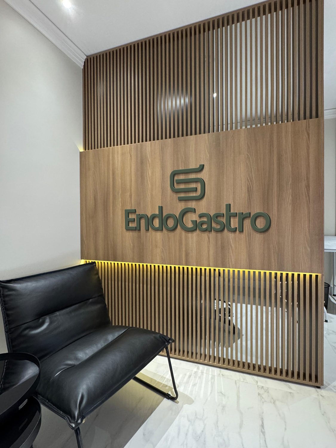 Sala de espera da clínica EndoGastro com painel de madeira e logo
